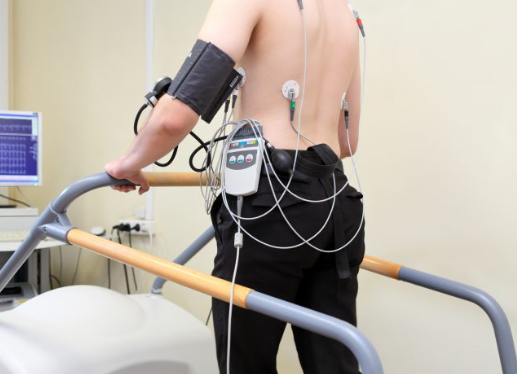 Diagram of a TMT cardiac stress test showing a patient on a treadmill with ECG electrodes and heart monitor